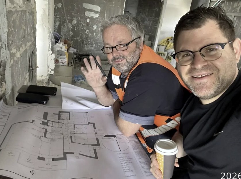 Aryeh Rapaport reviewing renovation blueprints on-site with a contractor