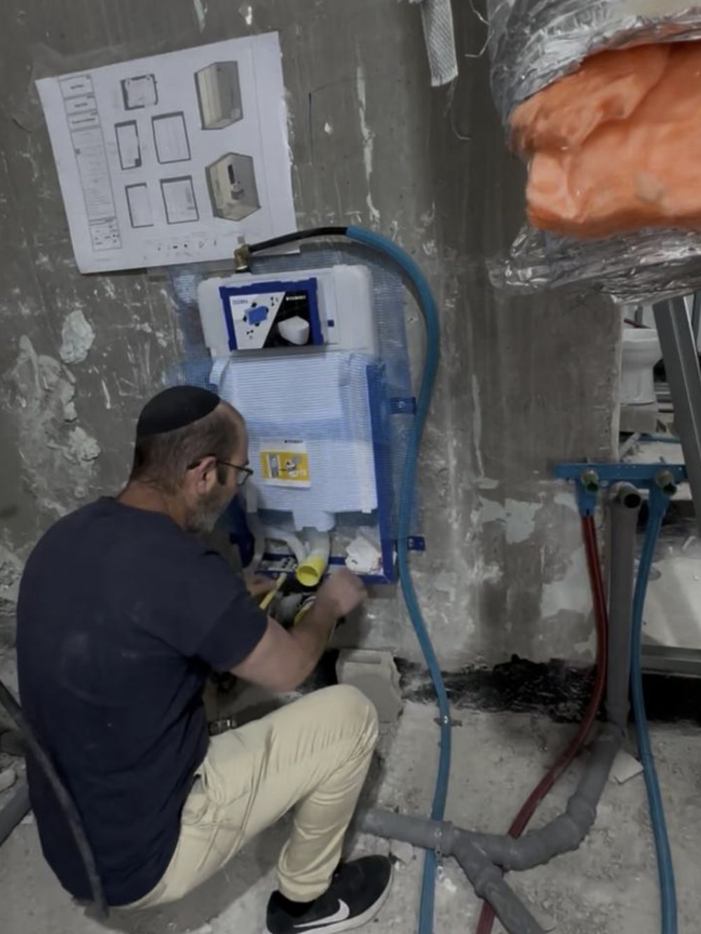 Plumber installing an in-wall toilet system during a renovation